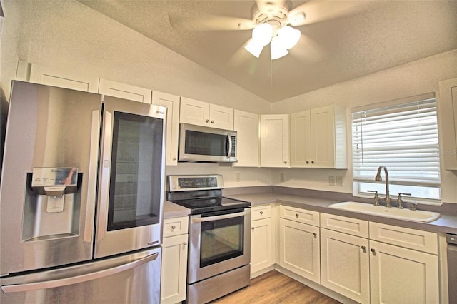 kitchen with lofted ceiling, sink, white cabinets, and appliances with stainless steel finishes