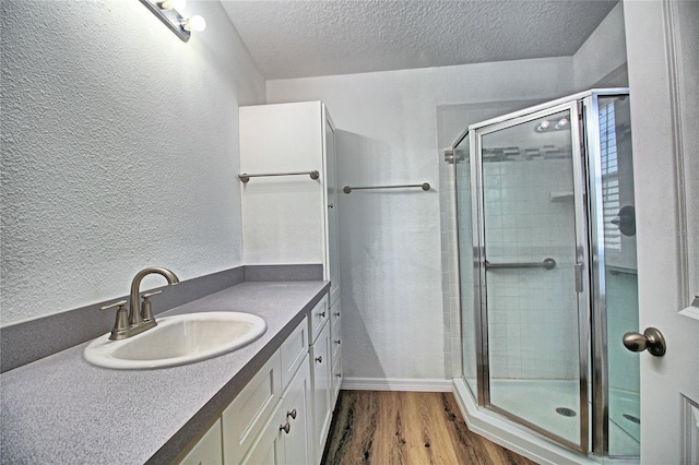 bathroom with vanity, hardwood / wood-style floors, a textured ceiling, and walk in shower