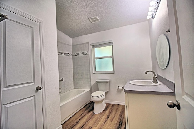 full bathroom with hardwood / wood-style flooring, vanity, a textured ceiling, toilet, and tiled shower / bath