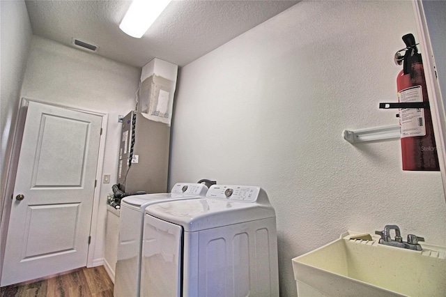 washroom featuring hardwood / wood-style flooring, sink, washing machine and dryer, and a textured ceiling