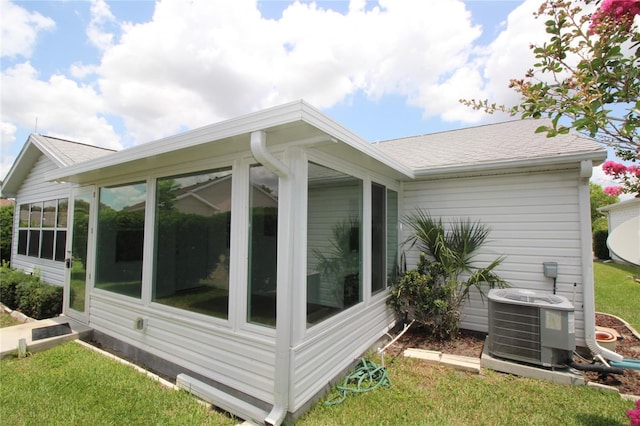 view of home's exterior with a sunroom, a yard, and central AC