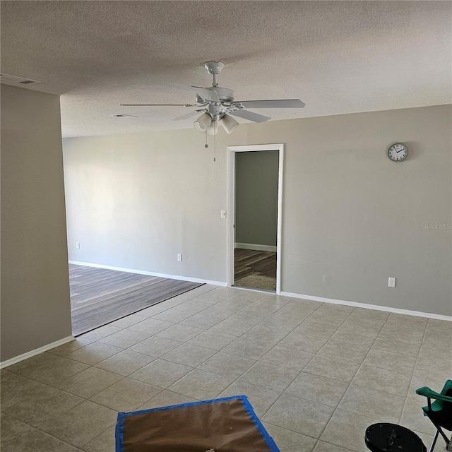 spare room featuring ceiling fan, light tile patterned floors, and a textured ceiling