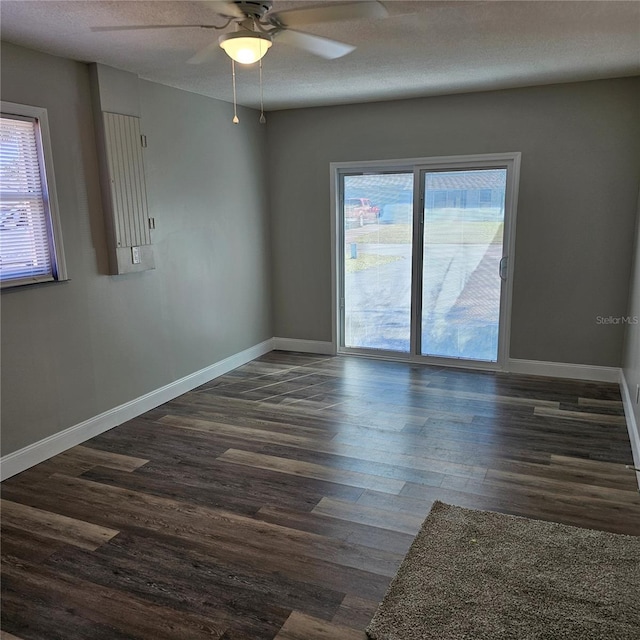 spare room with ceiling fan, a healthy amount of sunlight, a textured ceiling, and dark hardwood / wood-style floors