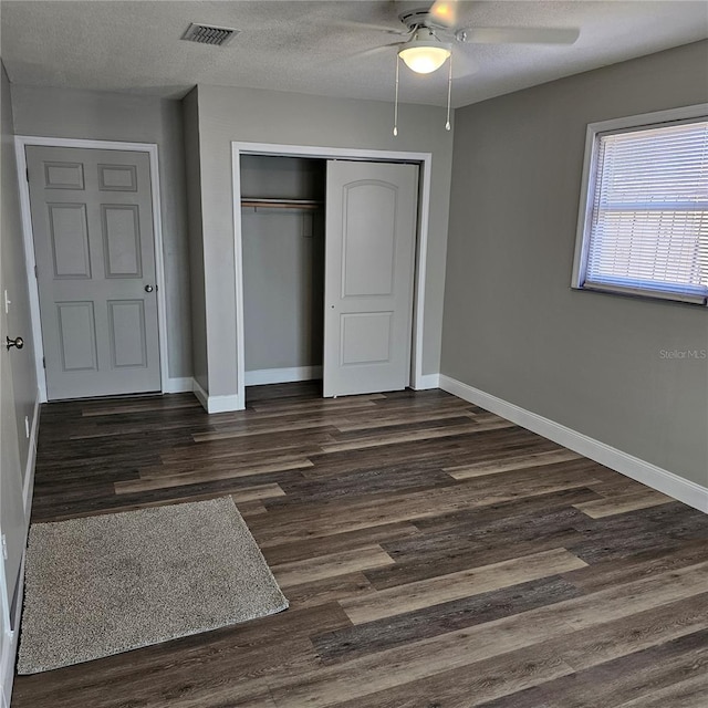 unfurnished bedroom with ceiling fan, dark hardwood / wood-style flooring, a closet, and a textured ceiling