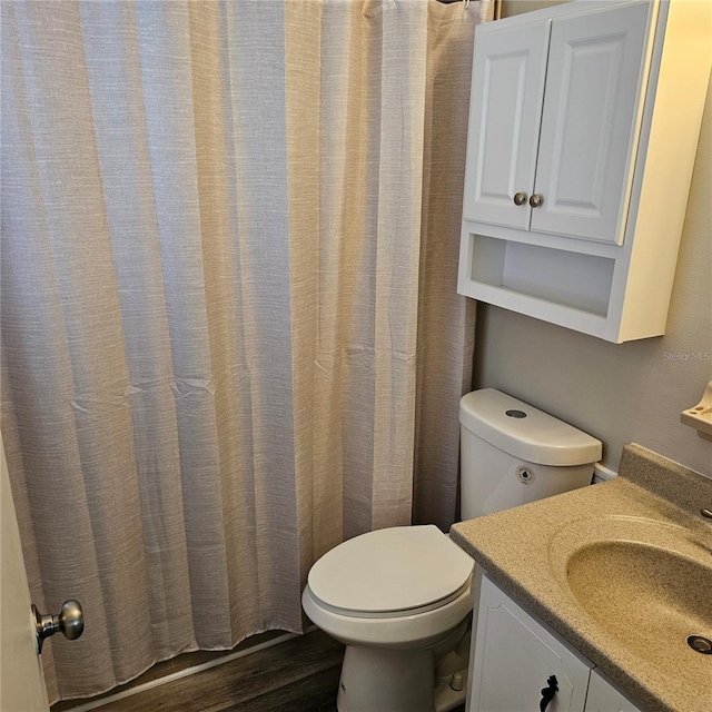 bathroom with vanity, toilet, and hardwood / wood-style floors