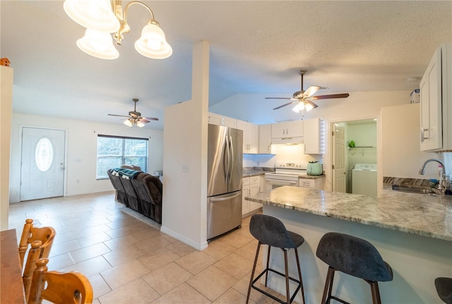 kitchen featuring sink, stainless steel refrigerator, white cabinets, washer / clothes dryer, and kitchen peninsula