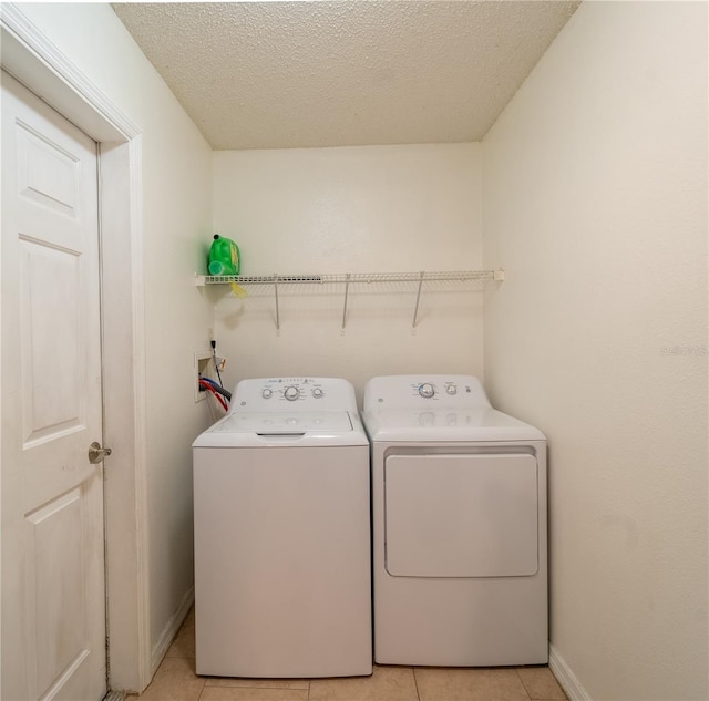 laundry area featuring light tile patterned floors, washing machine and dryer, and a textured ceiling