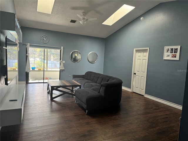 living room featuring high vaulted ceiling, a skylight, dark hardwood / wood-style flooring, ceiling fan, and a textured ceiling