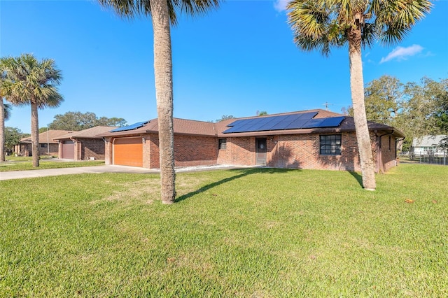 ranch-style home with a garage, a front lawn, and solar panels