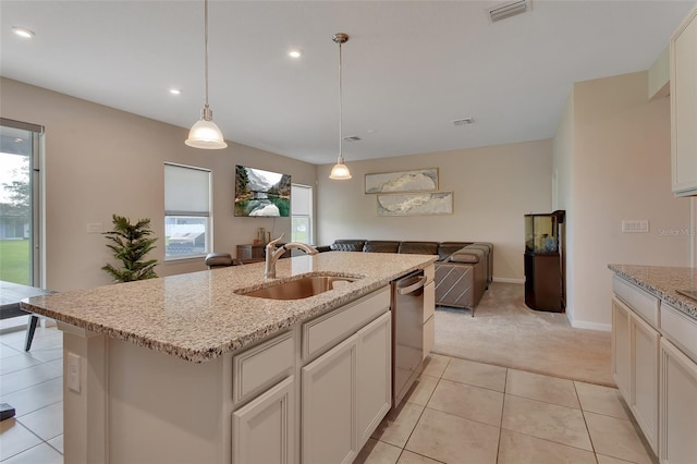 kitchen featuring sink, dishwasher, pendant lighting, light stone countertops, and a kitchen island with sink