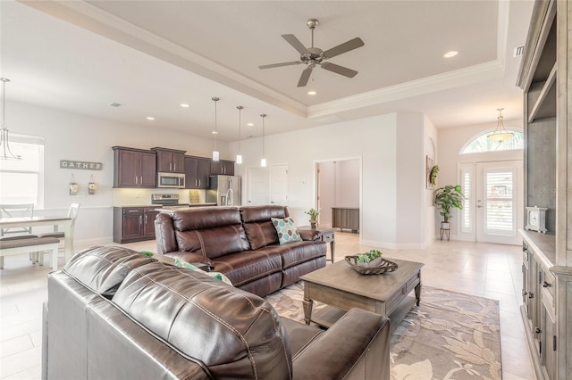 tiled living room with ceiling fan, ornamental molding, and a tray ceiling