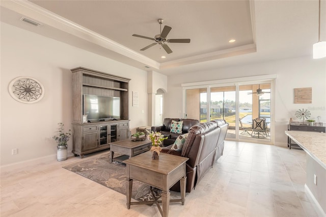 living room with crown molding, ceiling fan, and a tray ceiling