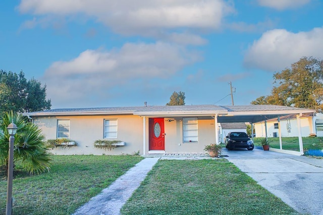 single story home featuring concrete driveway, a front yard, a carport, and stucco siding