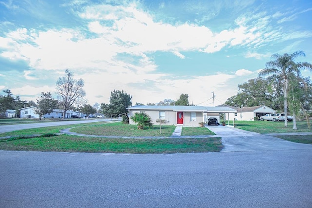 view of front of home with an attached carport, driveway, a residential view, and a front yard