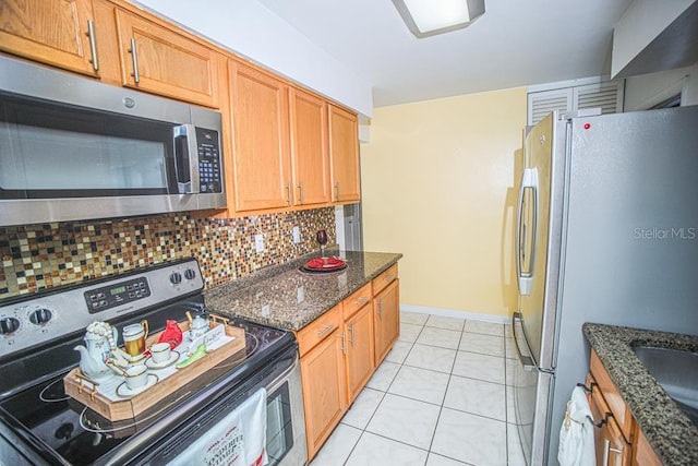 kitchen featuring backsplash, appliances with stainless steel finishes, light tile patterned flooring, and dark stone countertops