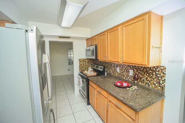 kitchen with stainless steel appliances, tasteful backsplash, light tile patterned flooring, and dark stone counters