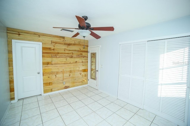 empty room with ceiling fan and wood walls