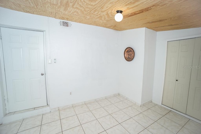 empty room with light tile patterned flooring and wooden ceiling