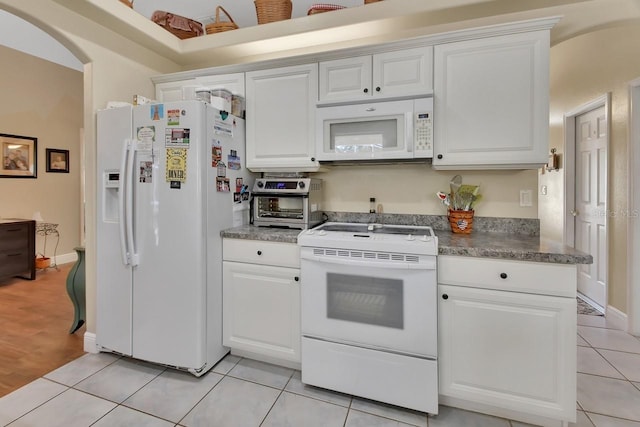 kitchen featuring white cabinetry, light tile patterned flooring, and white appliances