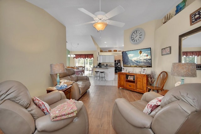 living room featuring ceiling fan with notable chandelier and light hardwood / wood-style flooring