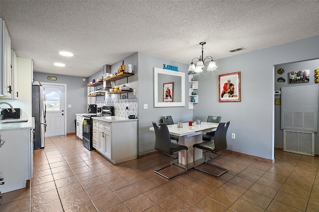 kitchen with stainless steel fridge, an inviting chandelier, electric range oven, white cabinets, and a kitchen bar