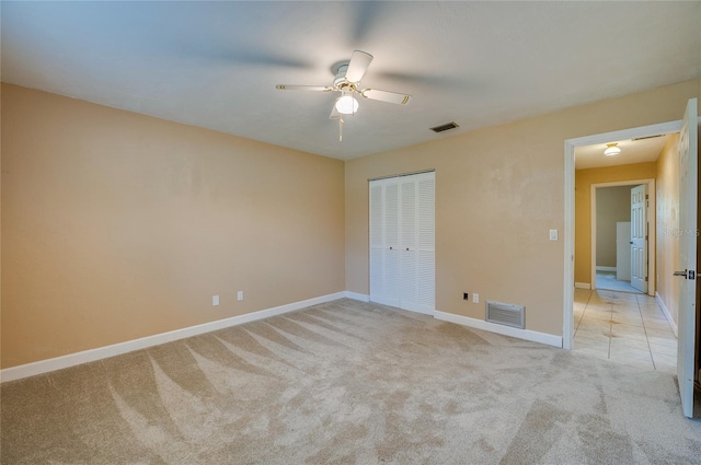 unfurnished bedroom featuring light colored carpet, ceiling fan, and a closet