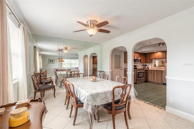 dining area featuring ceiling fan, ornamental molding, a textured ceiling, and light tile patterned floors