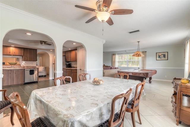 dining room featuring tile patterned flooring, crown molding, ceiling fan, and a textured ceiling