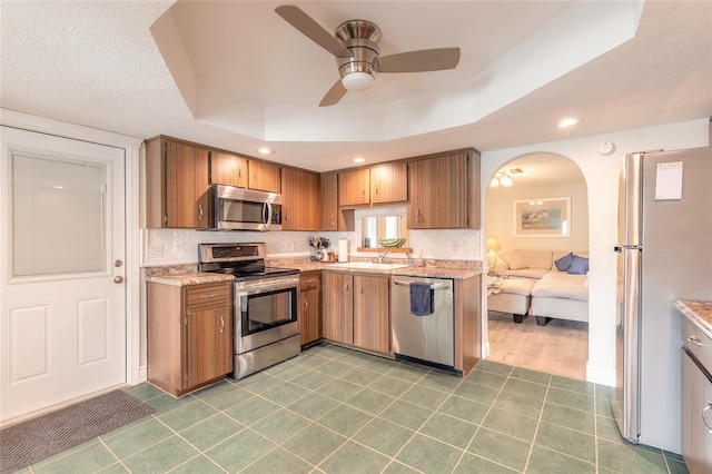 kitchen with stainless steel appliances, a raised ceiling, sink, and decorative backsplash