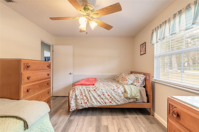 bedroom with ceiling fan, a textured ceiling, and light hardwood / wood-style floors