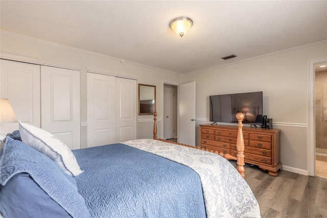 bedroom featuring hardwood / wood-style flooring, crown molding, a textured ceiling, and two closets