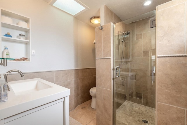 bathroom with tile patterned floors, toilet, an enclosed shower, tile walls, and vanity