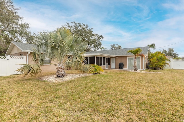 rear view of property featuring a sunroom and a lawn