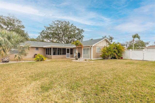 back of property with a sunroom and a yard