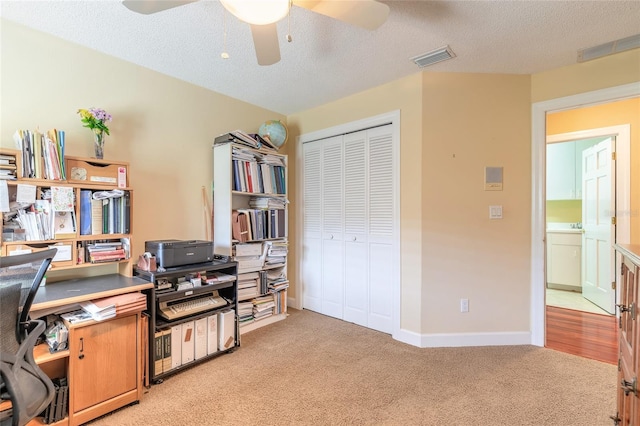 office area featuring light carpet, ceiling fan, and a textured ceiling