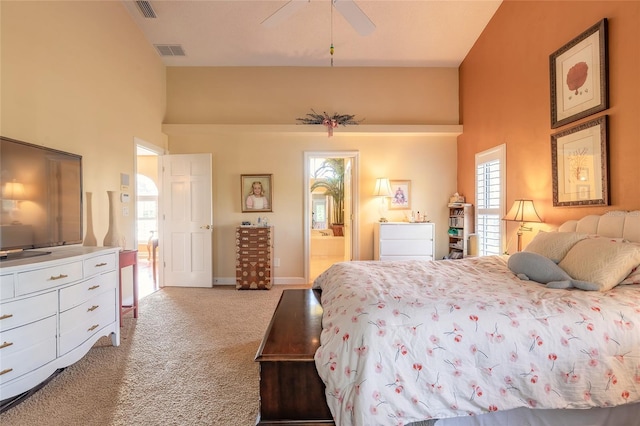 bedroom featuring connected bathroom, a towering ceiling, light colored carpet, and ceiling fan