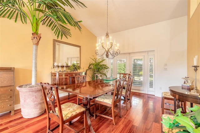 dining space featuring an inviting chandelier, high vaulted ceiling, and hardwood / wood-style floors