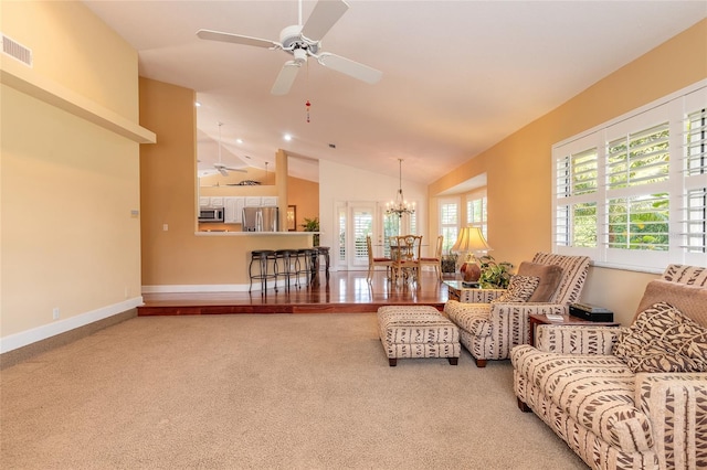 carpeted living room with ceiling fan with notable chandelier and vaulted ceiling