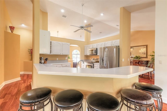 kitchen with white cabinetry, a kitchen bar, kitchen peninsula, and appliances with stainless steel finishes