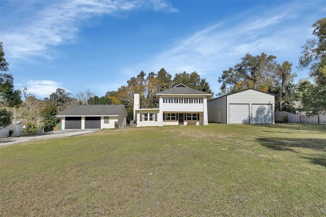 view of front of house with a garage, an outbuilding, and a front lawn