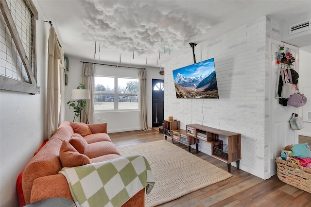 living room with hardwood / wood-style flooring and brick wall