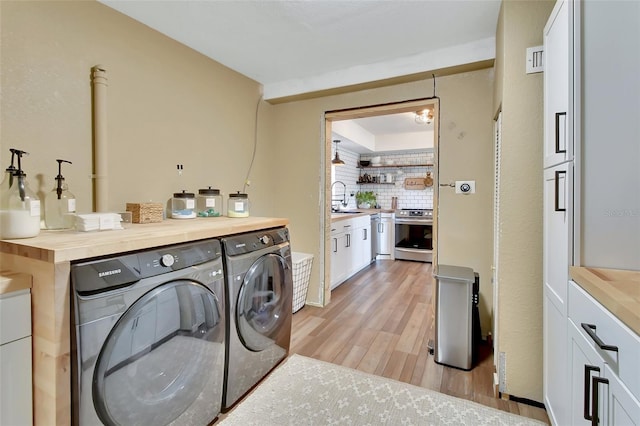 laundry area featuring independent washer and dryer, sink, and light wood-type flooring