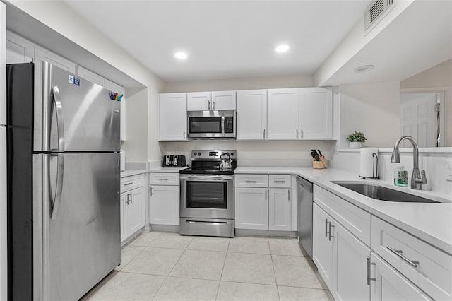 kitchen with white cabinetry, appliances with stainless steel finishes, sink, and light tile patterned floors