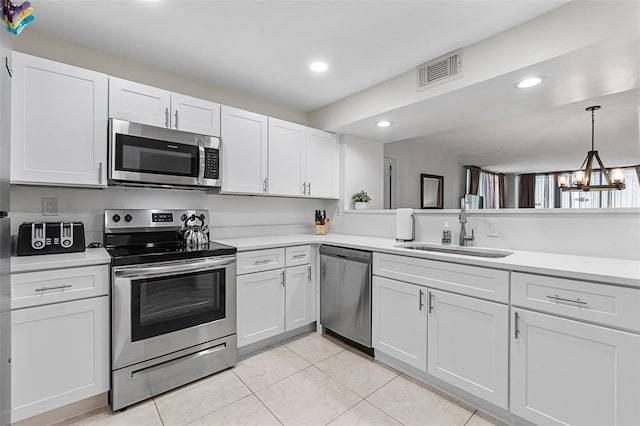 kitchen featuring white cabinetry, stainless steel appliances, an inviting chandelier, and sink