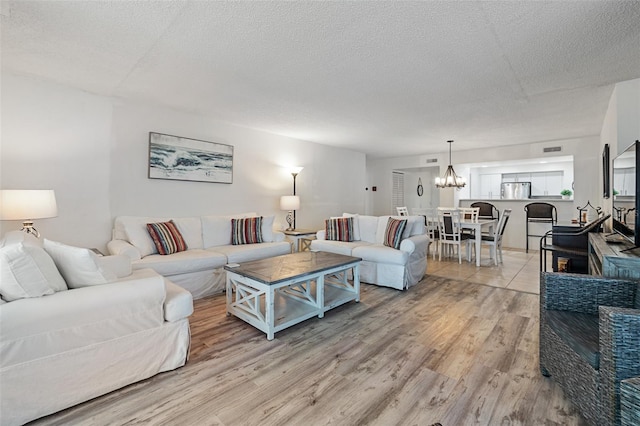 living room with an inviting chandelier, hardwood / wood-style floors, and a textured ceiling