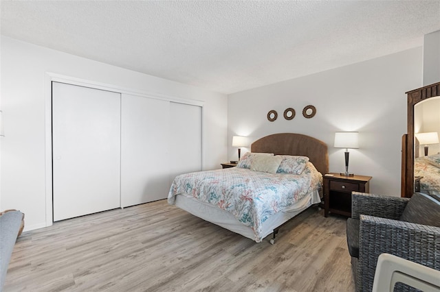 bedroom featuring a closet, light hardwood / wood-style flooring, and a textured ceiling