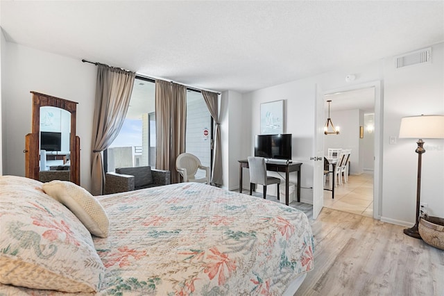 bedroom with a notable chandelier, a textured ceiling, and light wood-type flooring