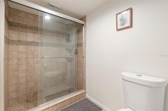 bathroom featuring a shower with door and toilet