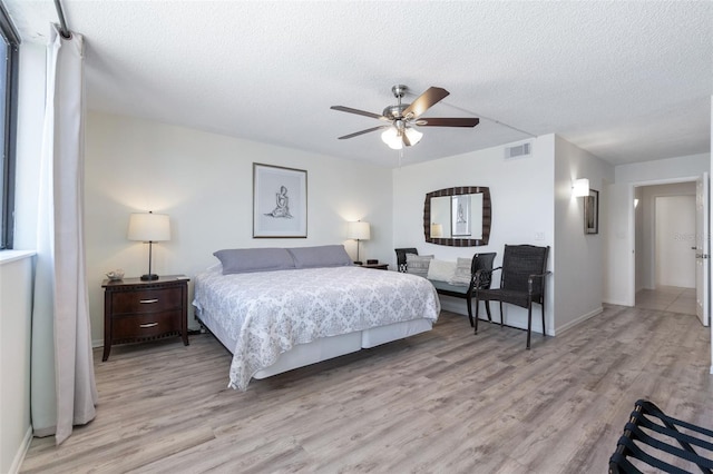 bedroom featuring ceiling fan, a textured ceiling, and light hardwood / wood-style floors