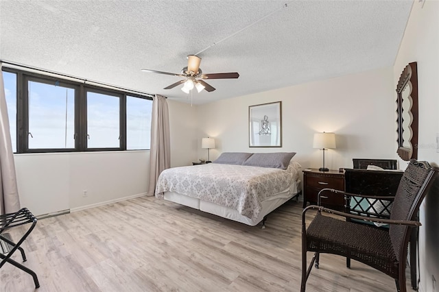 bedroom with ceiling fan, light hardwood / wood-style flooring, and a textured ceiling